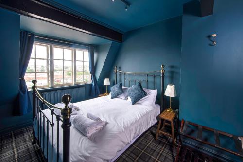 um quarto com uma cama com paredes azuis e uma janela em The Victoria Hotel em Scarborough