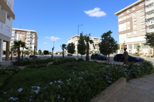 a person sitting on a sidewalk next to a field of flowers at DLX03 - Appartement Deluxe 2 chambres - Centre Ville Oujda in Oujda