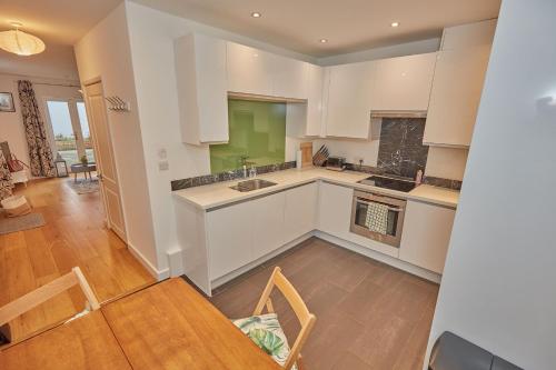 a kitchen with white cabinets and a table and chairs at Mews house in the centre of Henley-on-Thames in Henley on Thames