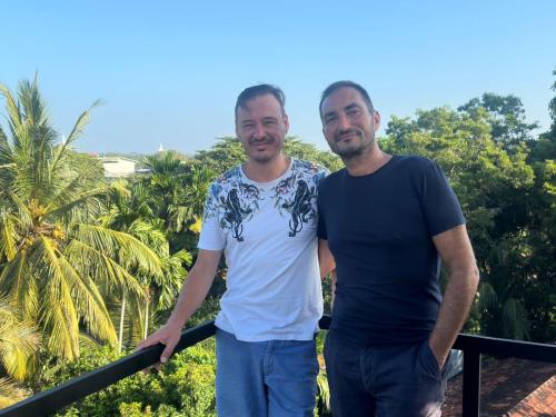 two men standing next to each other on a balcony at Emerald Home Stay in Anuradhapura