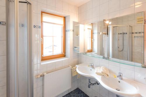 Baño blanco con lavabo y espejo en Hotel Pension Appartement Kristall en Tröpolach