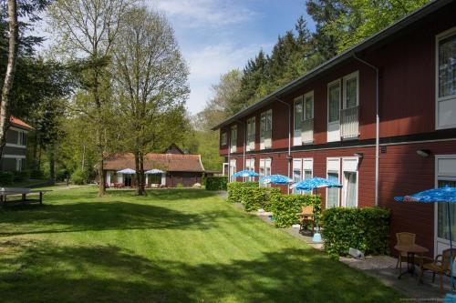 a building with a yard with umbrellas in front of it at Hotel de Stoppelberg in Beekbergen