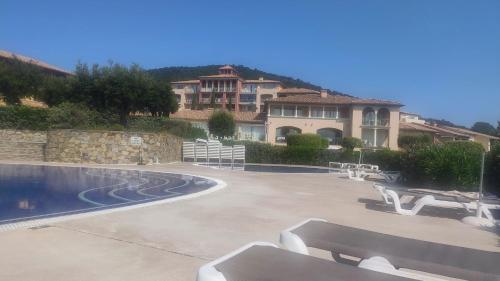 un bâtiment avec une piscine avec des bancs devant dans l'établissement Les Issambres, résidence standing - T3 Magnifique Vue Mer-Piscine Ste Maxime 7km, à Roquebrune-sur Argens