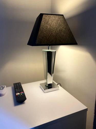 a lamp and a remote control sitting on a table at Dinorwic Lodge in Liverpool