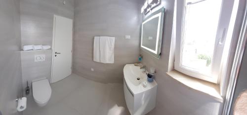 a white bathroom with a toilet and a sink at Slano Bay Apartments in Slano