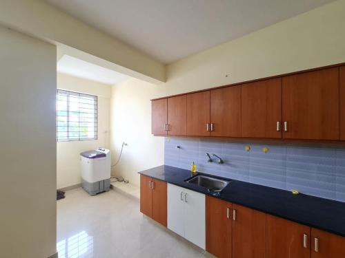 uma cozinha com armários de madeira e um lavatório em MSK Gardenia Service Apartments em Cochin