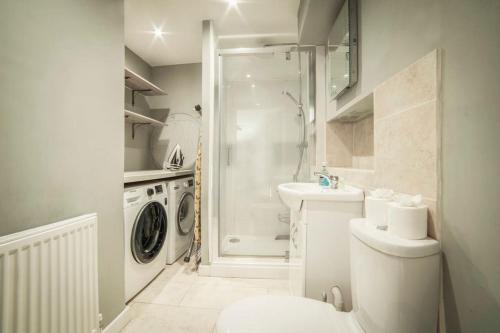 ein weißes Badezimmer mit einer Waschmaschine und einem Waschbecken in der Unterkunft Spacious 3 Bedroom Cottage nestled in Oxfordshire Countryside in Kirtlington