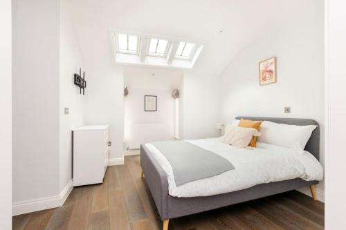 um quarto com uma cama com paredes brancas e pisos em madeira em Modern House in South Kensington em Londres