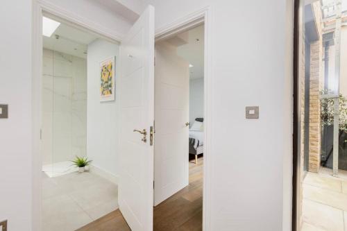 uma porta giratória num corredor branco com uma casa de banho em Modern House in South Kensington em Londres