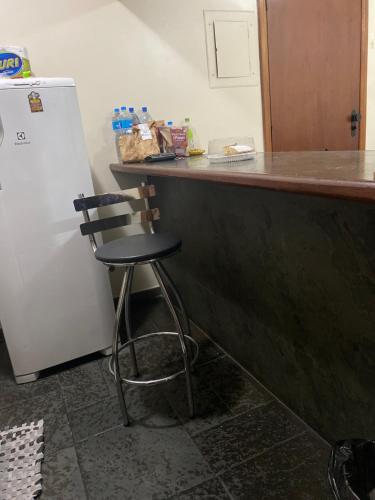 a kitchen with a counter and a chair next to a refrigerator at Flat em São Vicente in São Vicente