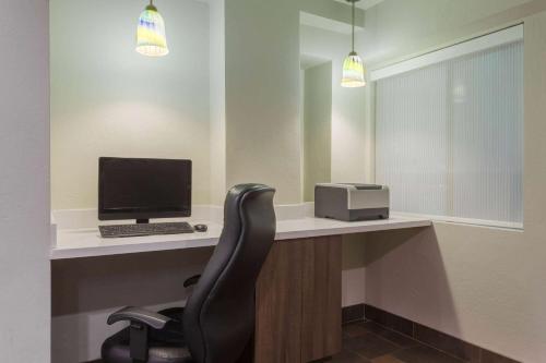 a office with a desk with a computer and a chair at Days Inn & Suites by Wyndham East Flagstaff in Flagstaff