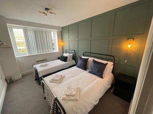 a bedroom with two beds with white sheets and blue pillows at Stylish 1-Bed Apartment in Swindon in Swindon