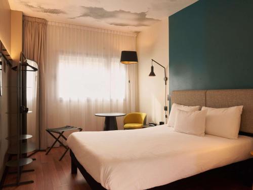 a hotel room with a bed and a chair at Ibis Madrid Aeropuerto Barajas in Madrid