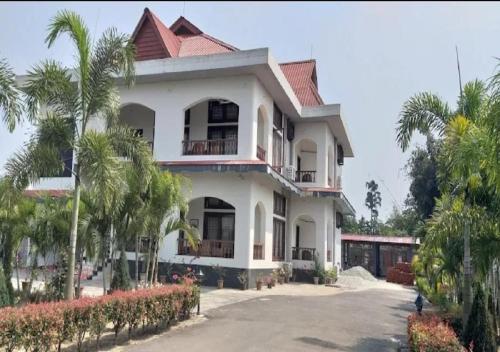 duży biały dom z palmami przed nim w obiekcie Chet Residency Namsai w mieście Namsai