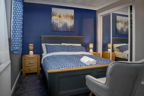 1 dormitorio azul con 1 cama y 1 silla en Raku House Ashford 5 beds - sleep 8 - Free parking and Wifi - Prime location for Families and Contractors, en Ashford