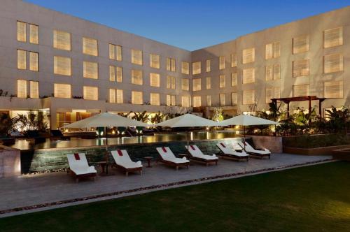 un hotel con sillas y sombrillas junto a una piscina en Hyatt Pune en Pune
