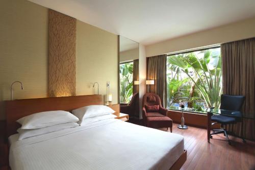 a bedroom with a bed and a desk and a window at Hyatt Pune in Pune