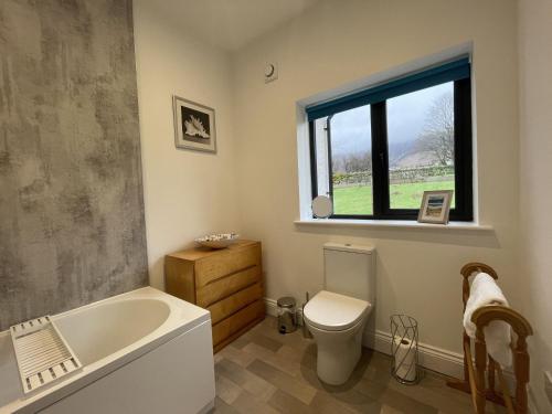 bagno con vasca, servizi igienici e finestra di Langrigg Cottage a Portinscale