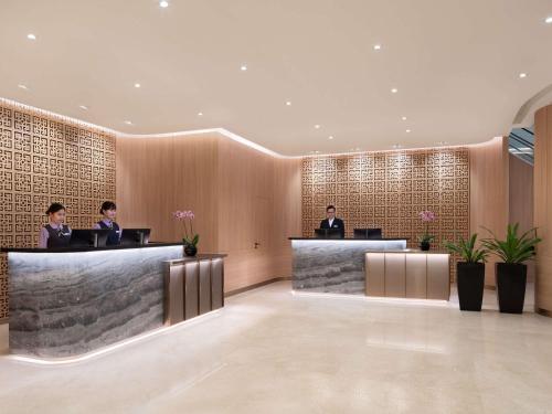 a lobby with two people sitting at the reception desks at Grand Mercure Singapore Roxy in Singapore