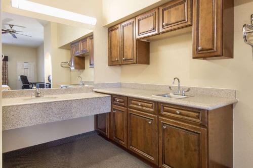 a kitchen with two sinks and wooden cabinets at Days Inn by Wyndham Baytown East in Baytown