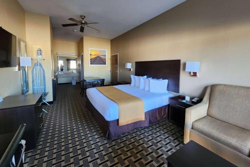 a hotel room with a large bed and a couch at Days Inn by Wyndham Baytown East in Baytown