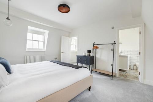 a white bedroom with a large bed and a mirror at Beautiful 3 bd house in Paddington in London