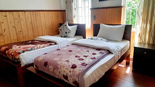 two beds in a room with wood paneling at Sapu's Mountain breeze Nuwara Eliya in Nuwara Eliya