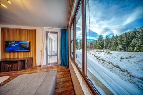 a living room with a large window and a tv at Oak Residence Hotel & Relax in Smolyan