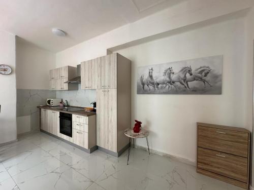 a kitchen with a painting of horses on the wall at Dolce Vita A 5 Minuti Dal Centro Con Parcheggio Privato Gratuito in Sanremo