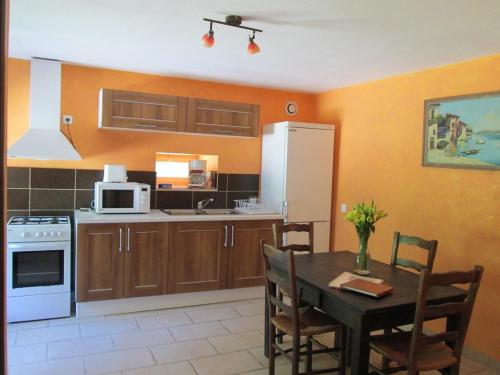 une cuisine avec une table et un réfrigérateur blanc dans l'établissement Gîte en bord d'étang et de rivière, à Beynat