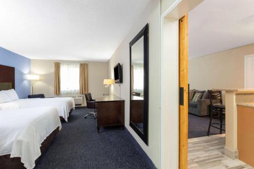 a hotel room with two beds and a living room at Days Inn and Suites by Wyndham Hammond, IN in Hammond