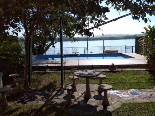 una mesa y taburetes frente a una piscina en Recanto da Vandeka as margens do Rio Grande, en Passos