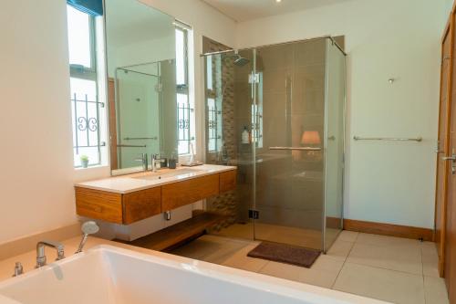 a bathroom with a tub and a sink and a shower at Stunning Belle Mare Beachfront luxury Apartment in Belle Mare