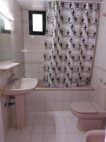 a bathroom with a sink and a toilet and a shower curtain at Furnished bedroom near Abu Dhabi Corniche in Abu Dhabi
