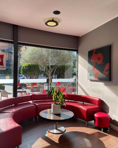 a waiting room with red couches and a table at Ibis Girona in Girona
