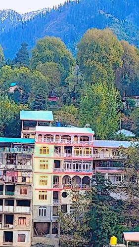 a pink building with trees and mountains in the background at Hotel Miandam Palace in Mingora