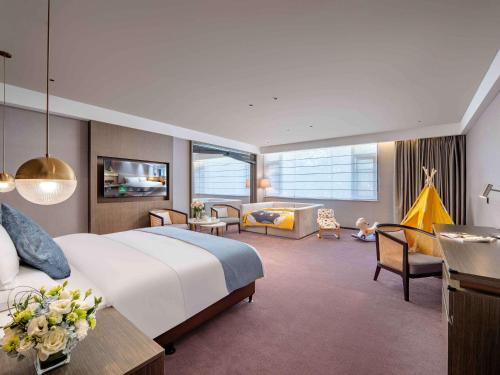 a bedroom with a large bed and a living room at Novotel Nantong Center in Nantong
