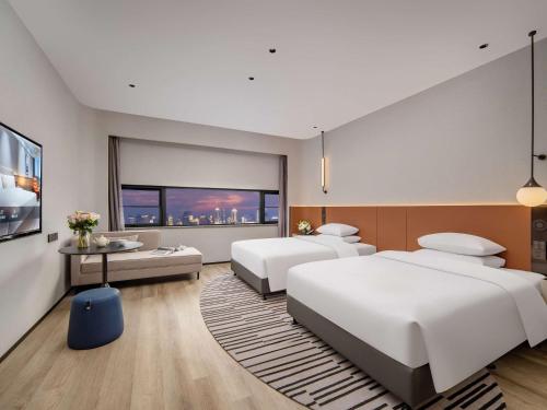 a bedroom with two beds and a table at Novotel Nantong Center in Nantong