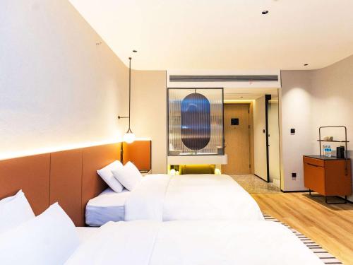 a hotel room with two beds and a window at Novotel Nantong Center in Nantong