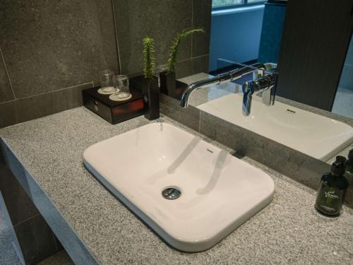 a bathroom counter with a white sink and a mirror at Novotel Nantong Center in Nantong