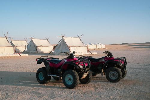 two atvs parked in the desert with tents in the background at Tzila Camp in Fayoum Center
