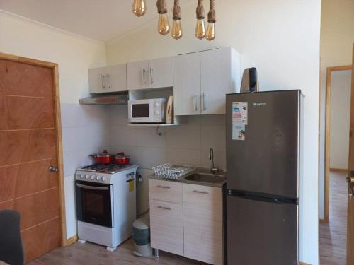 a kitchen with a refrigerator and a stove and a microwave at Cabaña en La Laguna in Valparaíso