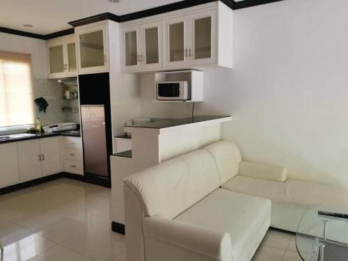 een woonkamer met een witte bank en een keuken bij DD Condominium in Ban Khlong Mae Nam