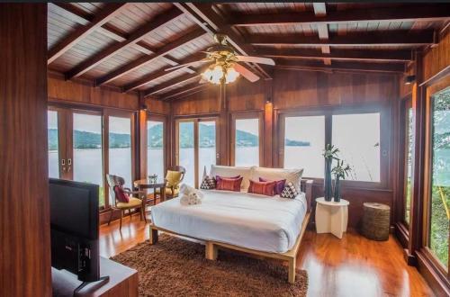 a bedroom with a bed and a tv and windows at Lang- Villa Amara，Kamala beach luxury villa in Surin Beach