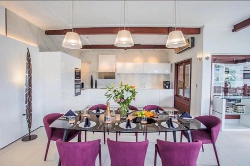 a dining room with a table and purple chairs at Lang- Villa Amara，Kamala beach luxury villa in Surin Beach