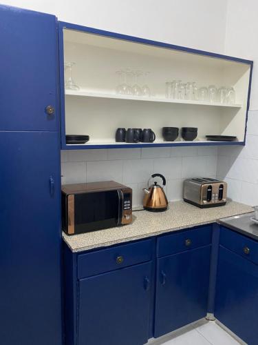 uma cozinha azul com um micro-ondas e uma chaleira. em Remarkable 1-Bed Apartment in Kensington Harare 