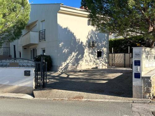 a white building with a gate in front of it at Delux 4 Stars Apartment Ariadne - 1 Min from Beach in Soline