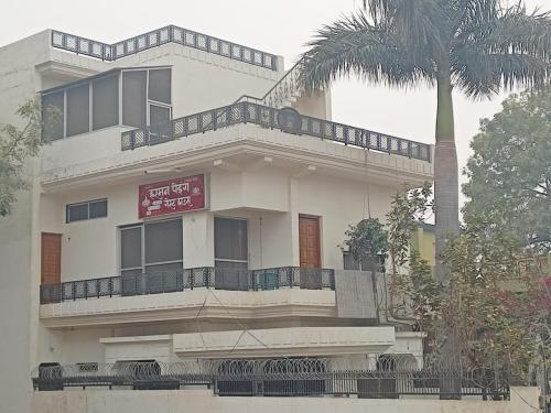 un bâtiment blanc avec un palmier en face dans l'établissement Harman paying guest house, à Ayodhya