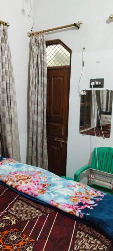 a bedroom with a bed and a chair and a door at Harman paying guest house in Ayodhya