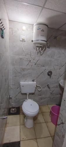 a bathroom with a toilet and a hair dryer on the wall at Harman paying guest house in Ayodhya